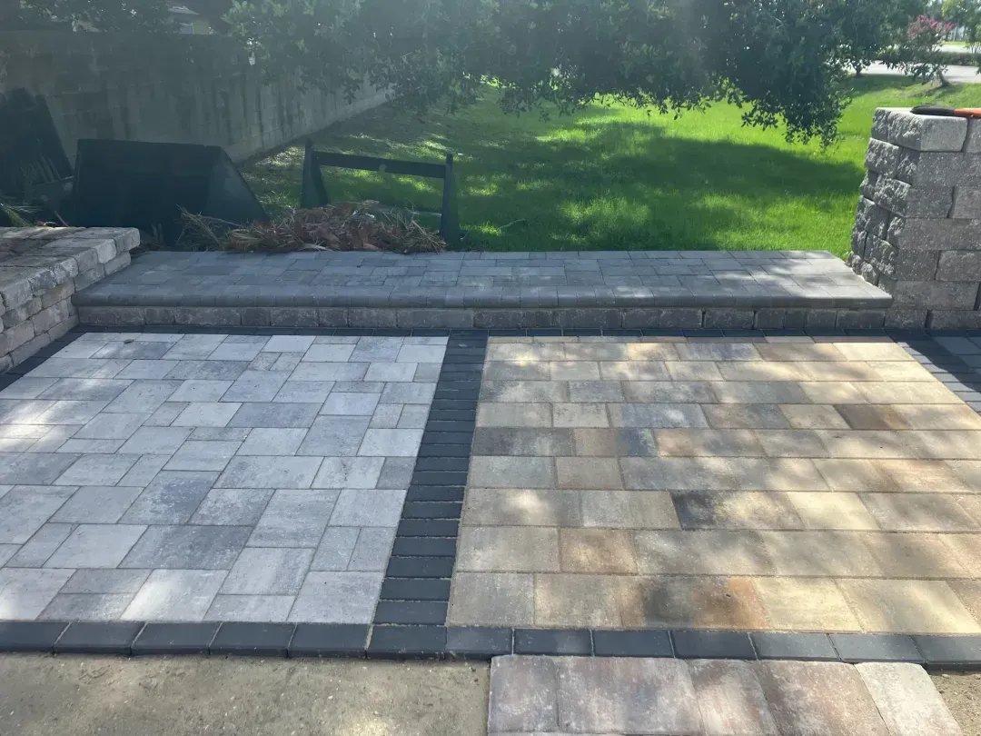 Two-tone paver patio with a charcoal soldier-course border, low seat wall, and column in a Central Florida backyard.