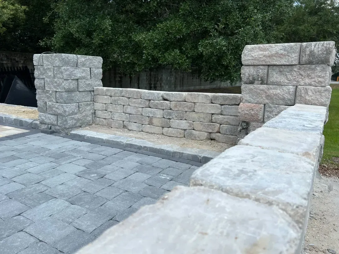 Finished retaining wall and matching paver columns framing a charcoal paver walkway.