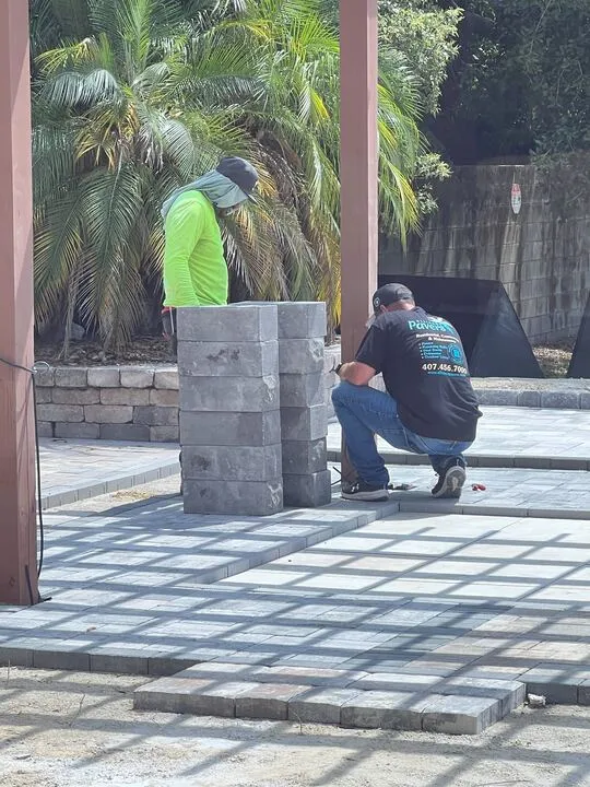 Two crew members setting a paver column on a commercial job site.