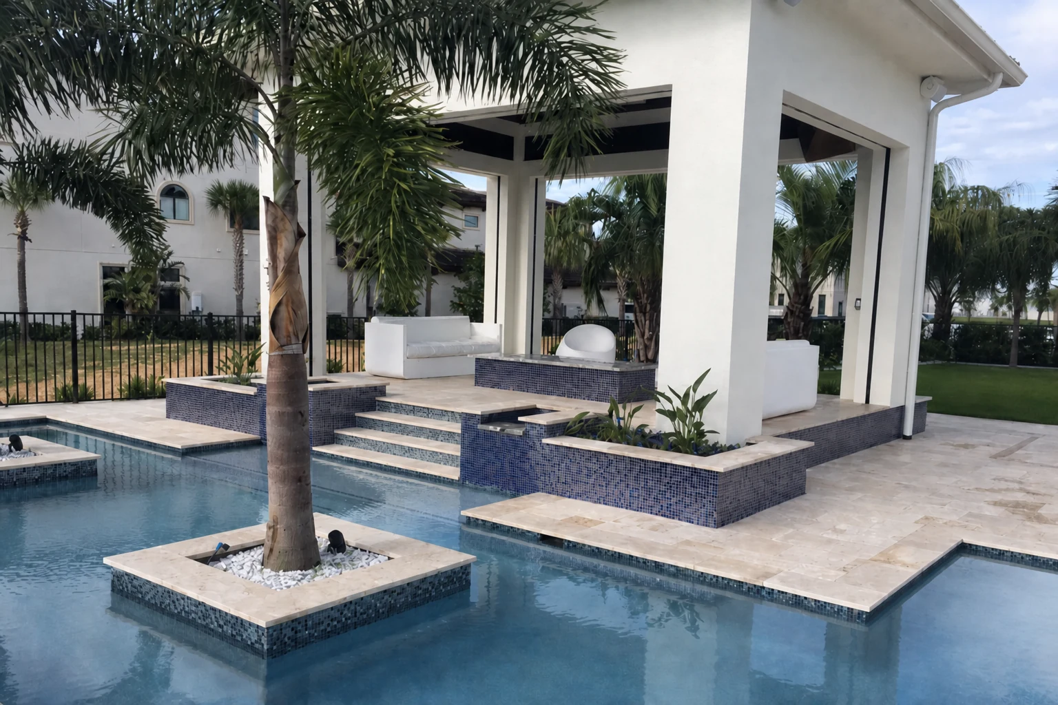 Travertine pool deck with blue glass tile spa and palm island
