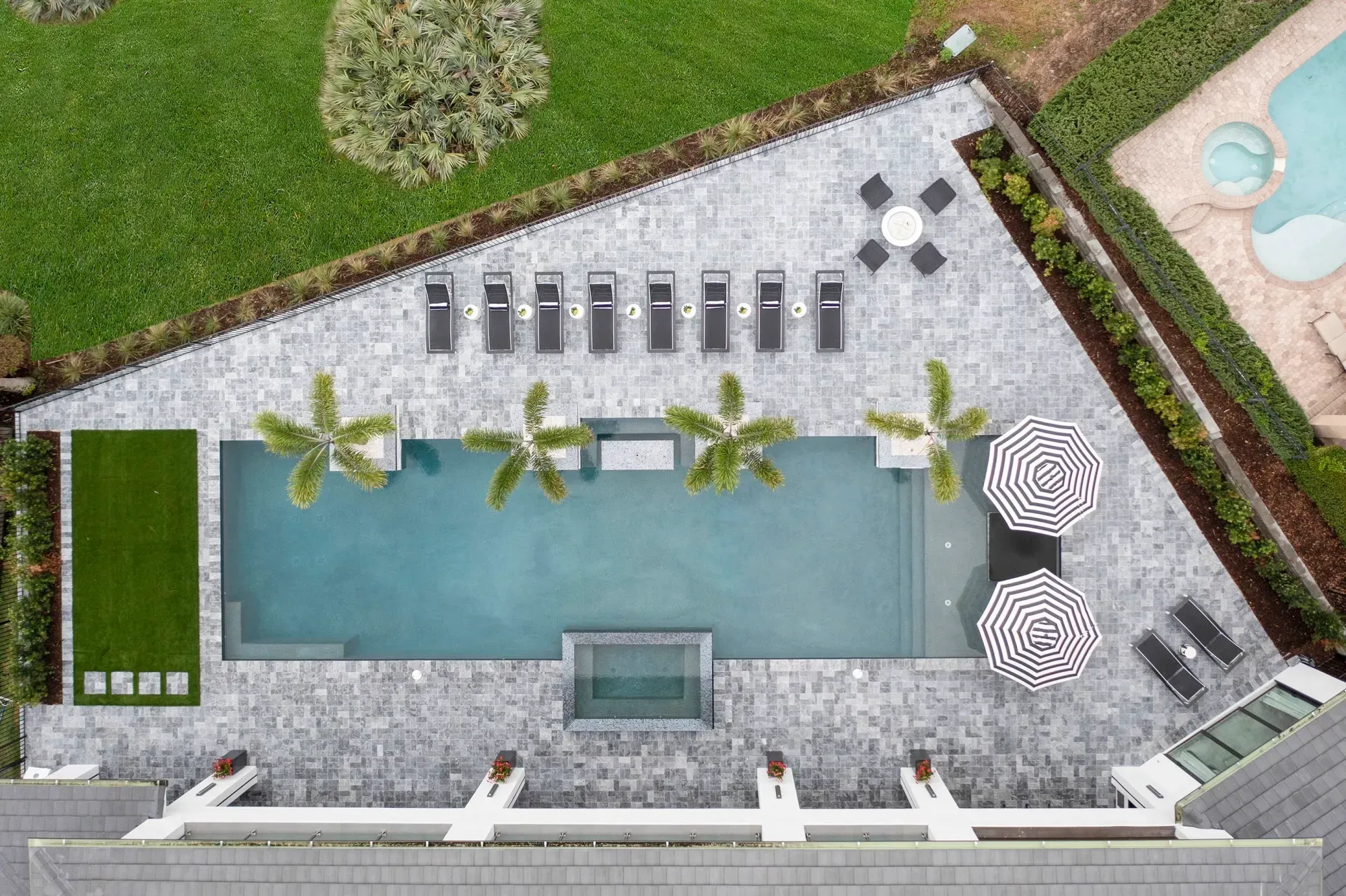 Resort-style paver pool deck with loungers and palms in Central Florida