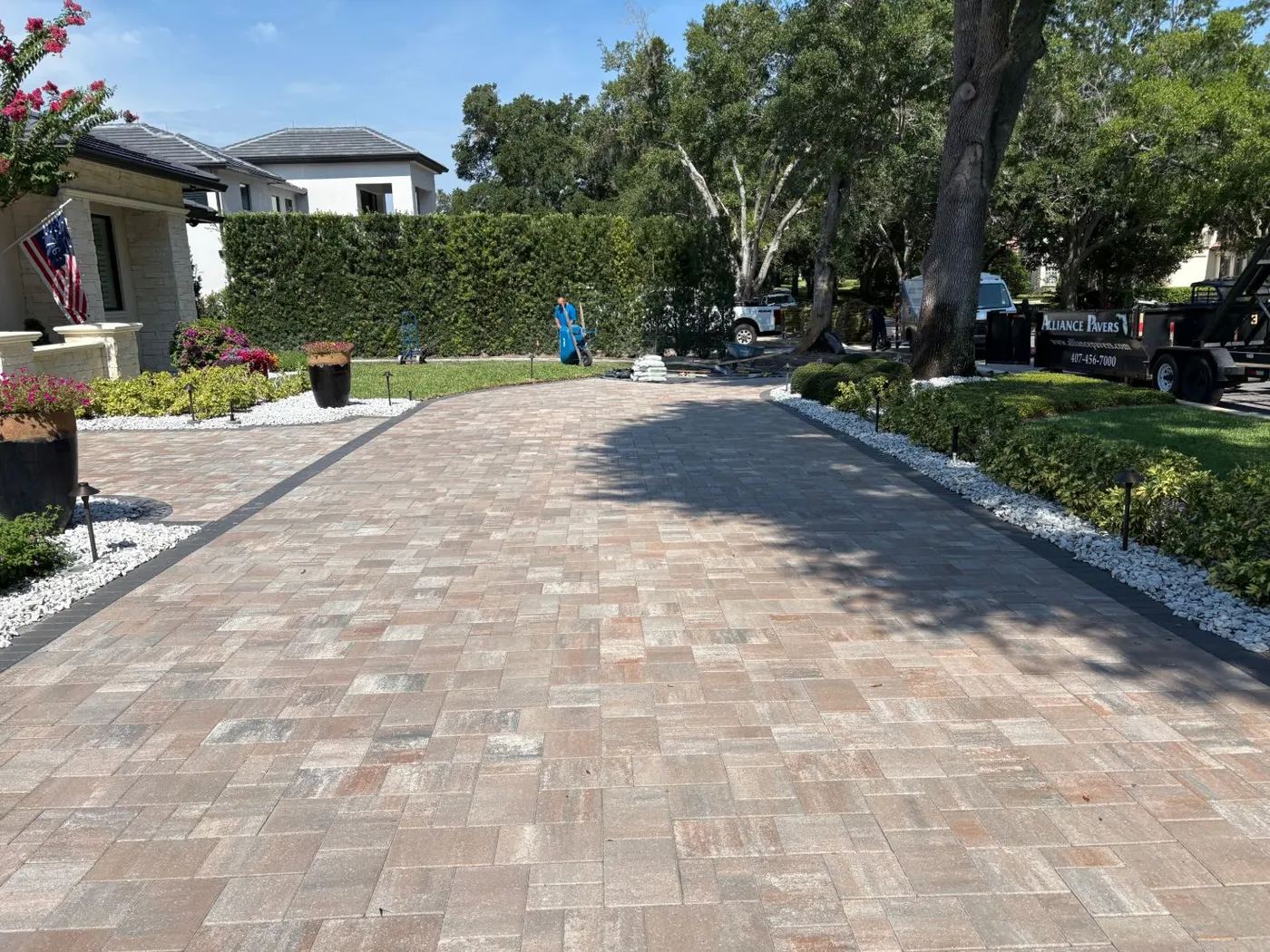 Alliance Pavers crew finishing a paver driveway with a dark border at an Isleworth home