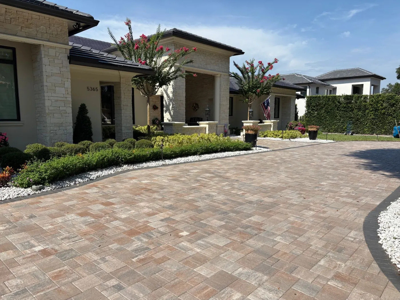 Paver entry driveway curving past a stone-fronted Isleworth home